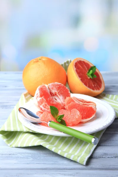 Zralé oloupané grapefruitů na desku, na barevný dřevěný stůl, na světlé pozadí — Stock fotografie