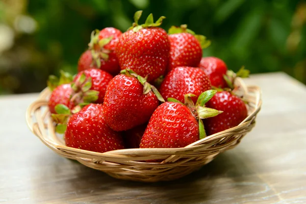 Fresas dulces maduras en canasta de mimbre en la mesa en el jardín — Foto de Stock