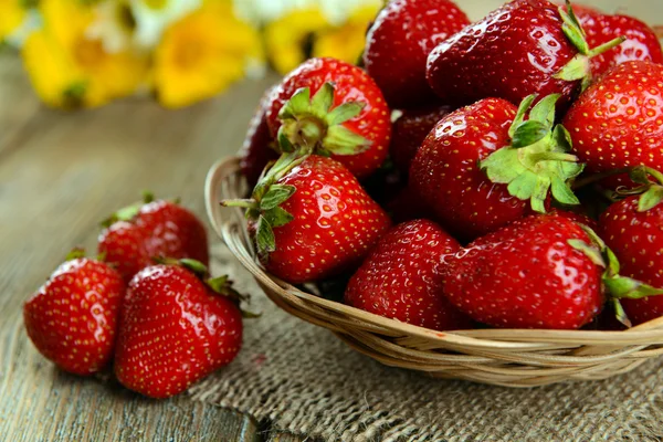 Zralé sladké jahody v proutěném koši na tabulka detail — Stock fotografie