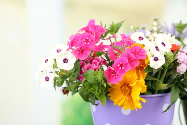 Buquê de flores coloridas em vaso decorativo, na mesa, sobre fundo brilhante — Fotografia de Stock