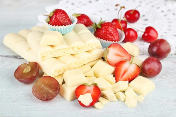Белая шоколадка со свежими ягодами, на фоне цвета дерева — стоковое фото