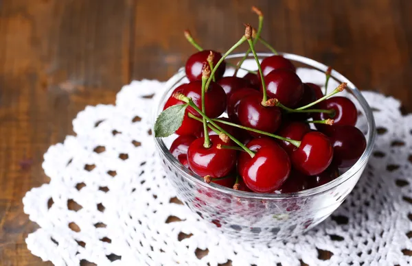 Cherries in color bowl on wooden background — Stock Photo, Image