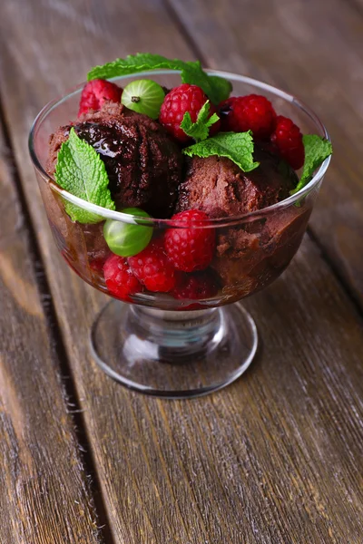 Chocolate ice cream with mint leaf and ripe berries in glass bowl, on color wooden background — Stock Photo, Image