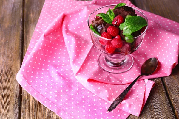 Gelato al cioccolato con foglia di menta e bacche mature in ciotola di vetro, su sfondo di legno a colori — Foto Stock