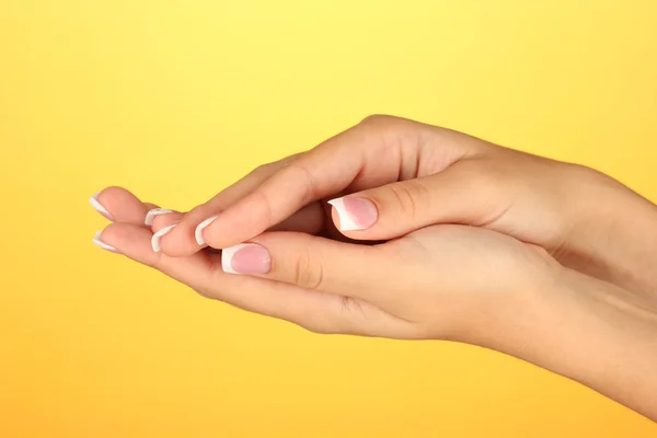 Mãos de mulher bonita com manicure francês no fundo amarelo — Fotografia de Stock