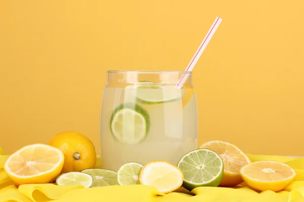 Citrusovou limonádu v bance skleněné citrusů kolem na žlutou látku na oranžovém pozadí — Stock fotografie