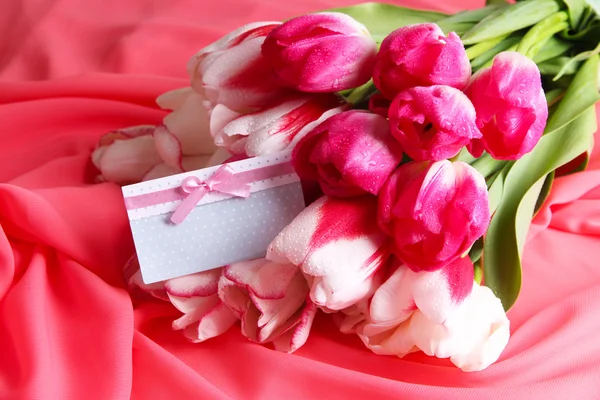 Красивые тюльпаны на фоне цветной ткани — стоковое фото