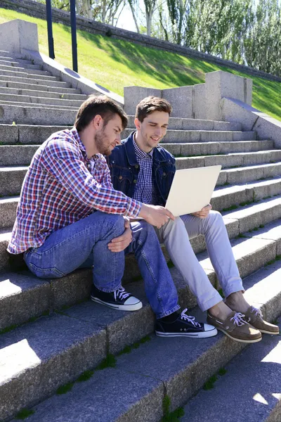 Students sitting on stairs in park — Stock Photo, Image