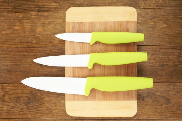 Kitchen knives and cutting board on wooden table — Stock Photo, Image