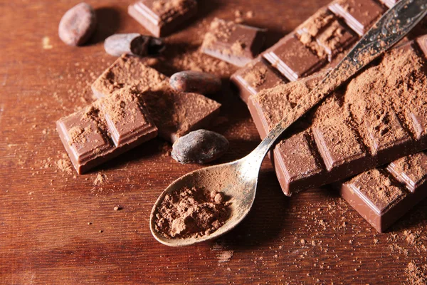 Cacao en polvo y chocolate negro sobre fondo de madera de color — Foto de Stock