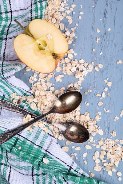 Apple with oatmeal and vintage spoons on napkin, on color wooden background — Stock Photo, Image