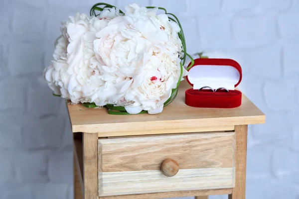 Beautiful wedding bouquet on   wooden stand on light wall background — Stock Photo, Image