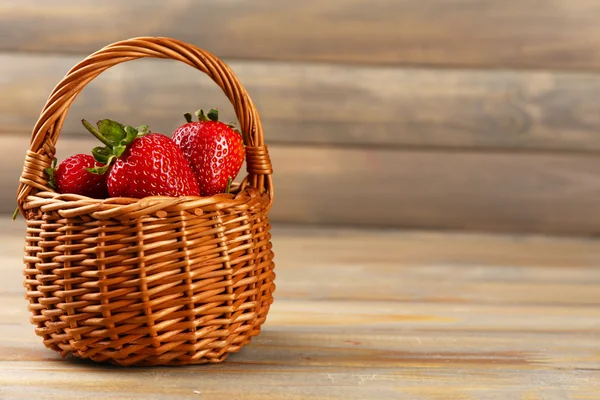 Red ripe strawberries in wicker basket on wooden background — Stock Photo, Image