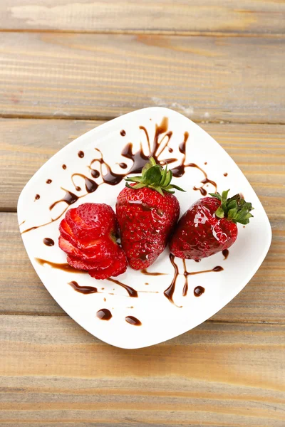 Red ripe strawberries with chocolate on wooden table — Stock Photo, Image