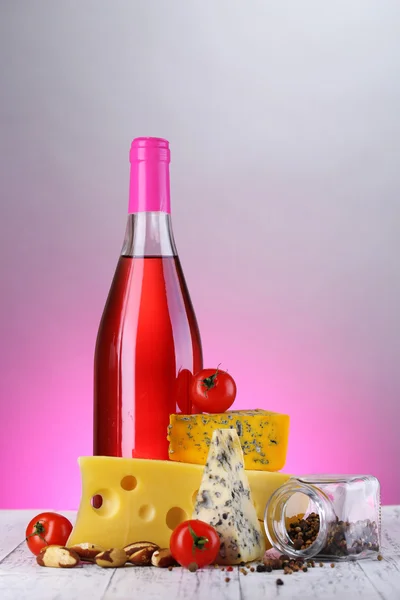 Vinho rosa e diferentes tipos de queijo no fundo colorido — Fotografia de Stock