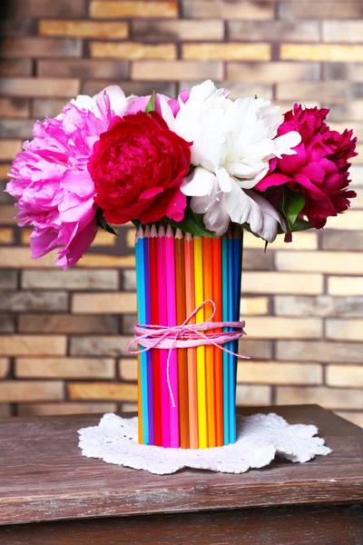 Bellissimi fiori in colorato vaso matite su sfondo muro di mattoni — Foto Stock