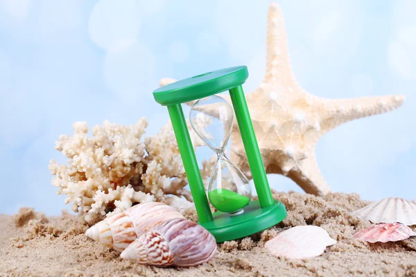 Hourglass in sand on bright background — Stock Photo, Image