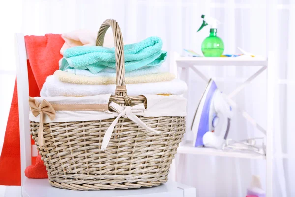 Colorful towels in basket on chair, on home interior background — Stock Photo, Image