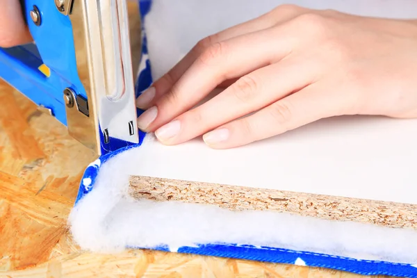 Fastening fabric and board using construction stapler — Stock Photo, Image