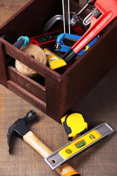 Деревянный ящик с различными инструментами, на деревянном фоне — стоковое фото