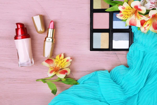Ögonskugga, läppstift och blommor på färg trä bakgrund — Stockfoto
