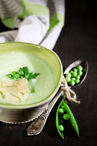 Soupe de petits pois savoureuse sur table en bois avec une lumière sombre — Photo