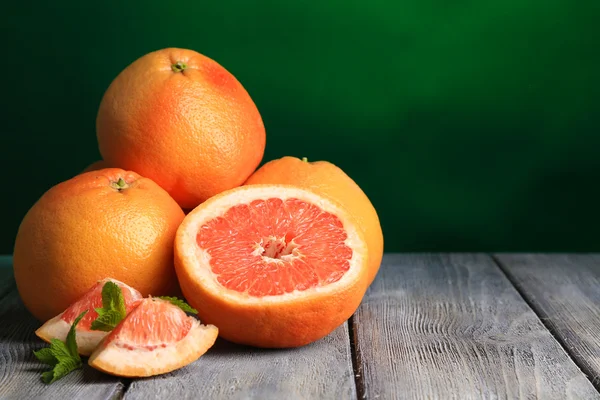 Ripe grapefruits on wooden board, on dark color background — Stock Photo, Image