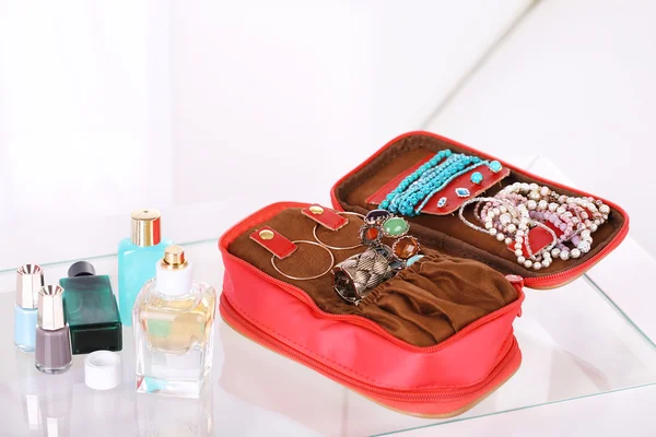 Bolso con accesorios y perfumes en botellas sobre mesa sobre fondo interior de casa — Foto de Stock