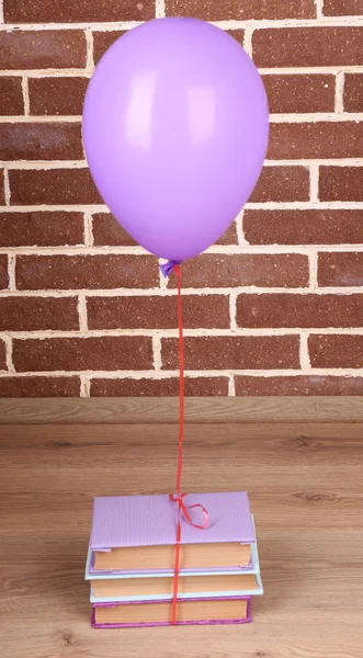 Kleur ballon met boeken over bakstenen muur achtergrond — Stockfoto