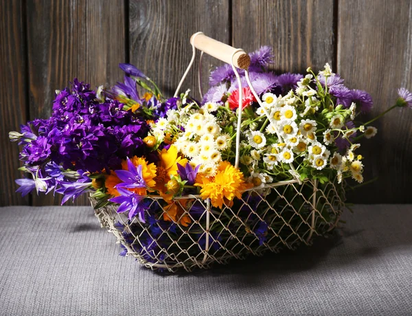 Hermosas flores silvestres en cesta sobre fondo de madera — Foto de Stock