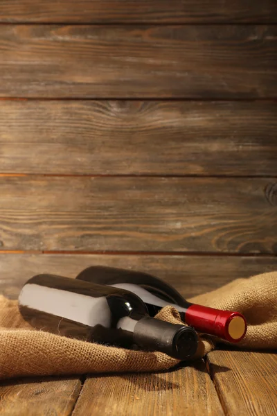 Lahví vína na dřevěné pozadí — Stock fotografie