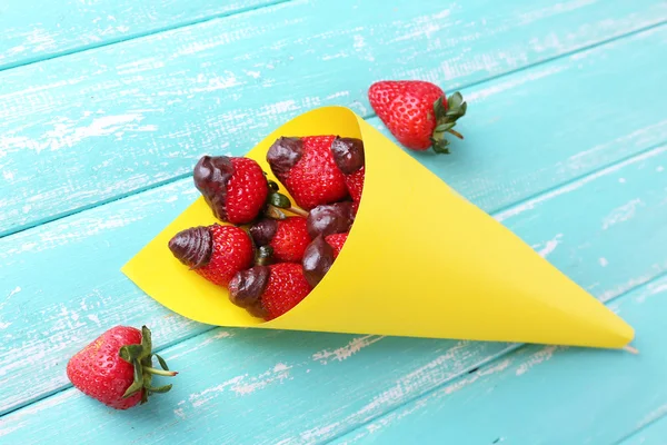 Aardbei in chocolade op spiesjes in papieren zak op tabel close-up — Stockfoto