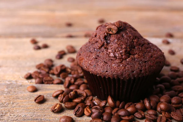 Chocolate muffin and coffee grains on wooden background — Stock Photo, Image