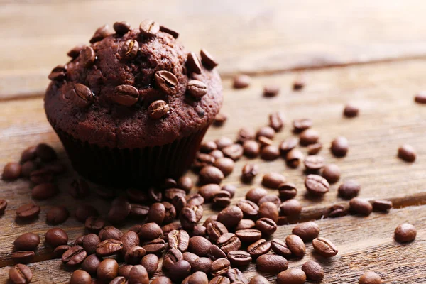 Choklad muffin och kaffe korn på trä bakgrund — Stockfoto