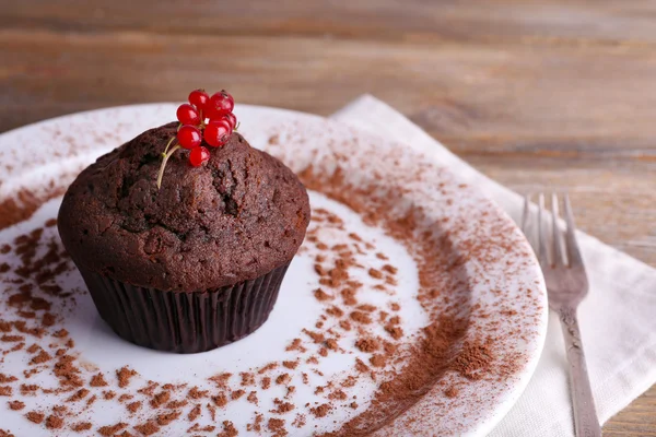 Chocolate muffin with red currant on plate on wooden background — Stock Photo, Image