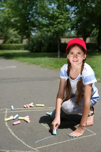 Cute girl drawing with chalk on asphalt — Stock Photo, Image