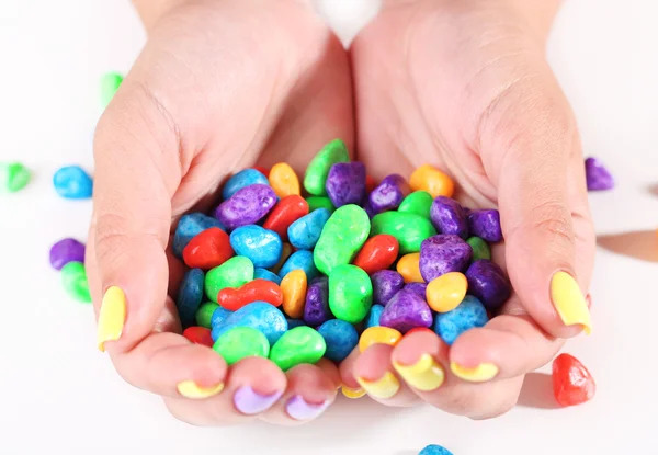 Mani femminili con eleganti unghie colorate che tengono caramelle multicolore, isolate su bianco — Foto Stock