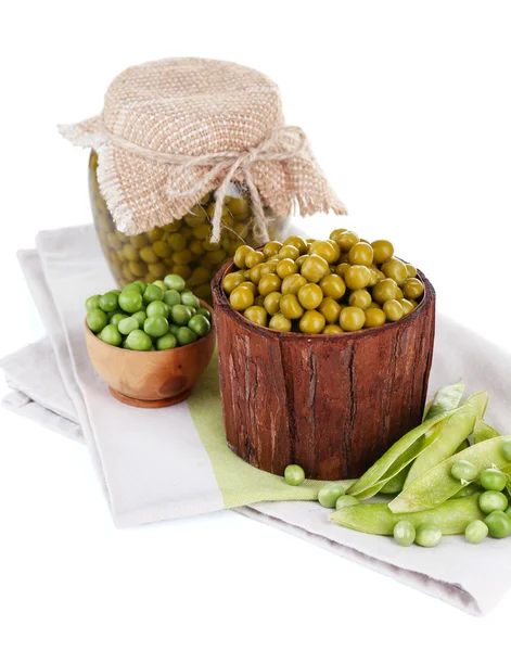 Piselli freschi e in scatola in ciotola e vaso di vetro su tovagliolo, isolati su bianco — Foto Stock