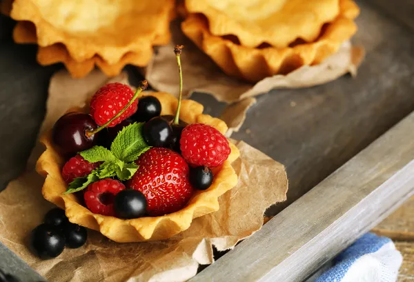 Tasty tartlets with berries on wooden tray — Stock Photo, Image