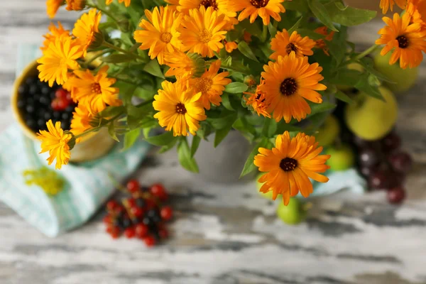 Kwiaty i owoce na drewnianym stole — Zdjęcie stockowe
