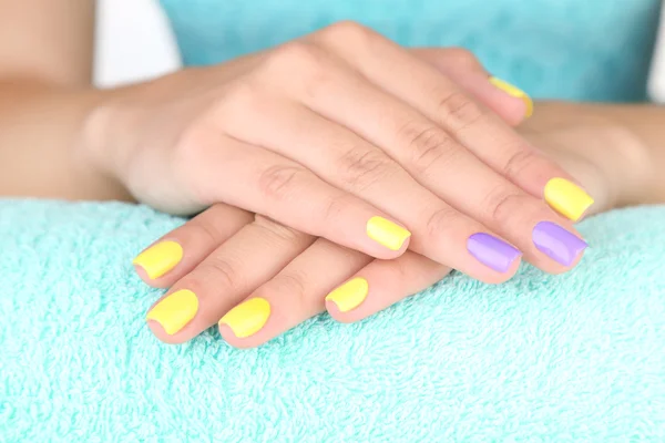 Female hand with stylish colorful nails, on color towel, close-up — Stock Photo, Image