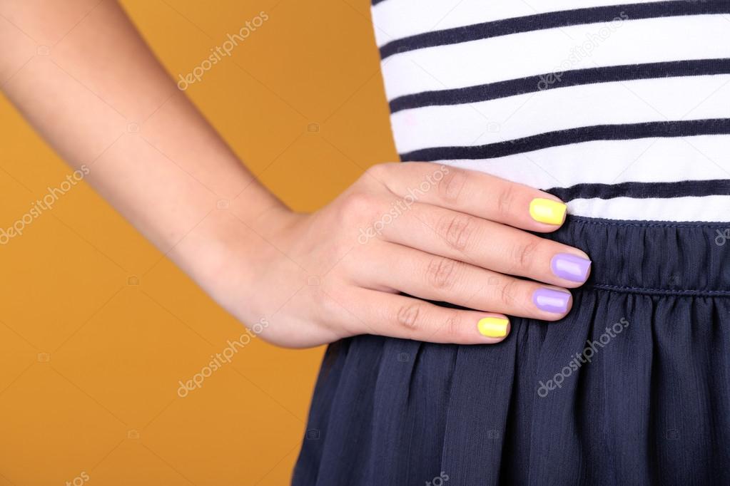 Female hand with stylish colorful nails, close-up, on color background