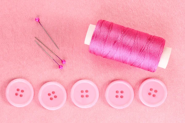 Boutons à coudre colorés avec fil sur tissu rose — Photo