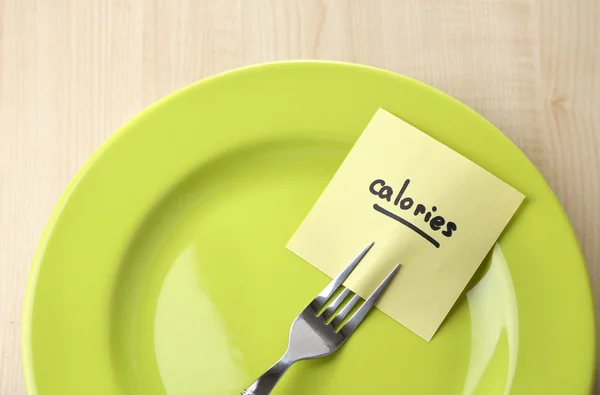 Note paper with message  attached to fork, on plate, on wooden background — Stock Photo, Image