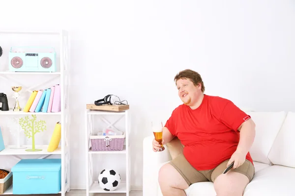 Lazy overweight male sitting on couch and watching television — Stock Photo, Image