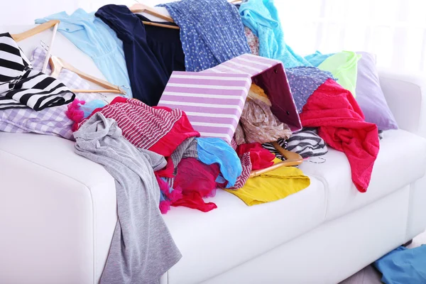 Berantakan warna-warni pakaian di sofa pada latar belakang cahaya — Stok Foto
