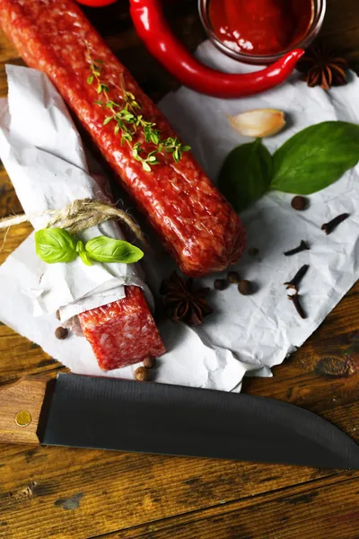 Salsicha de salame saboroso e especiarias em fundo de madeira — Fotografia de Stock