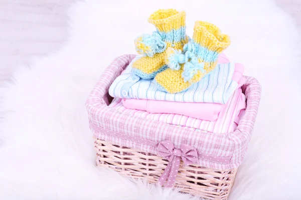 Baby clothes in basket on floor in room — Stock Photo, Image