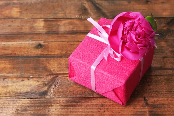 Presente rosa com arco e flor na mesa de madeira close-up — Fotografia de Stock