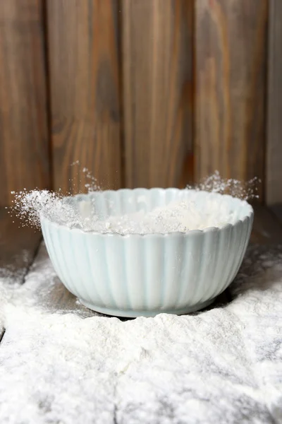 Mehl in Schüssel auf Tisch auf Holzgrund — Stockfoto